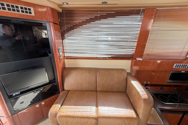 Slide: The Image of Interior of 2007 Sea Ray 36 Sedan Bridge with sofa, TV, and wooden cabinetry. - 21