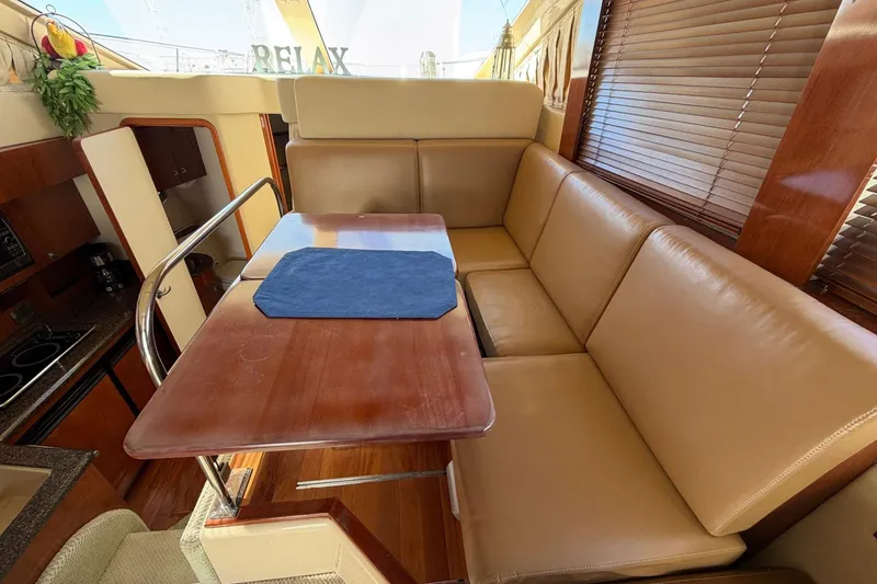 Slide: The Image of Luxurious interior of 2007 Sea Ray 36 Sedan Bridge with leather seating and wooden table. - 23
