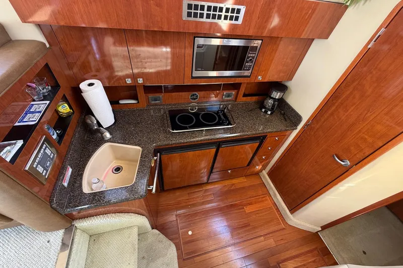 Slide: The Image of 2007 Sea Ray 36 Sedan Bridge kitchen with wood cabinetry, sink, stove, and microwave. - 25
