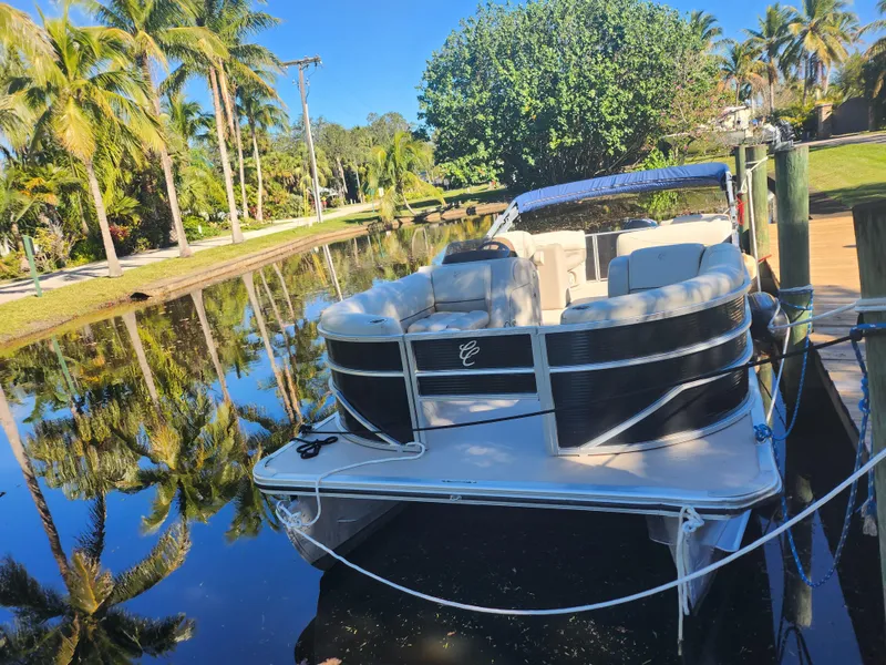 Slide: The Image of 2020 Cypress Cay Seabreeze 232 pontoon boat docked by palm trees. - 2