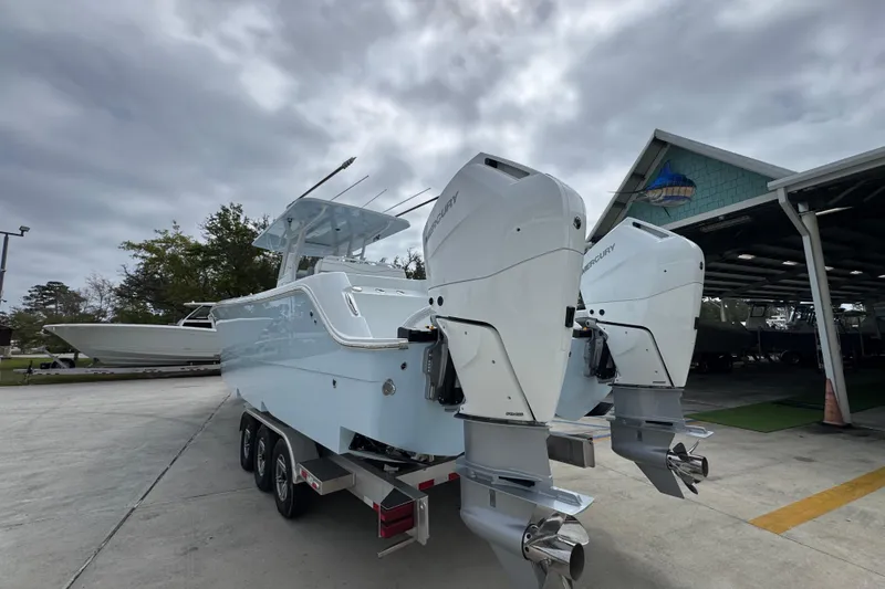 Slide: The Image of 2026 Invincible 33 Catamaran with dual Mercury engines on a trailer, under cloudy skies. - 15