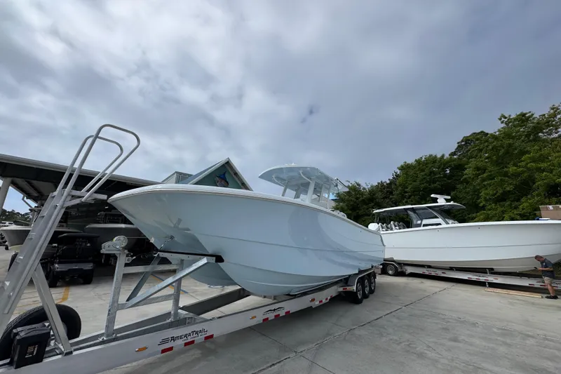 Slide: The Image of 2026 Invincible 33 Catamaran on trailer, parked outdoors under cloudy sky. - 4