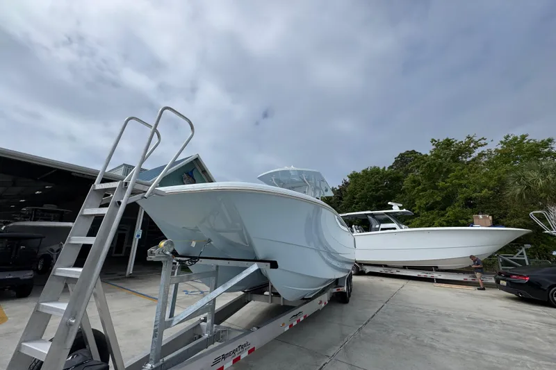 Slide: The Image of 2026 Invincible 33 Catamaran on trailer, parked outdoors under cloudy sky. - 5