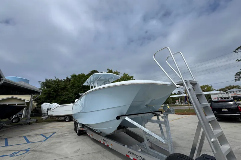 Slide: The Image of 2026 Invincible 33 Catamaran on trailer, parked outdoors under cloudy sky. - 7