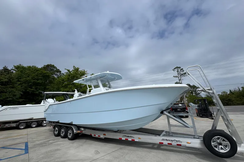 Slide: The Image of 2026 Invincible 33 Catamaran on trailer, parked outdoors under cloudy sky. - 8