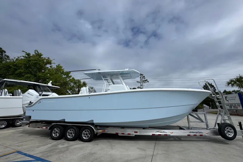 Slide: The Image of 2026 Invincible 33 Catamaran on trailer, parked outdoors under cloudy sky. - 9