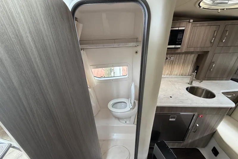Slide: The Image of Interior of 2022 Regal 33 XO boat featuring compact bathroom and modern kitchenette. - 17