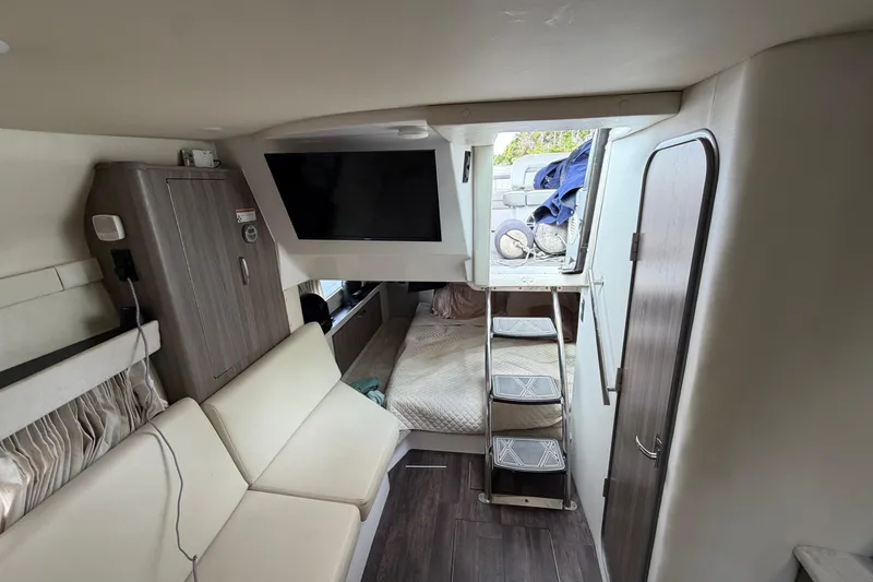 Slide: The Image of Interior of a 2022 Regal 33 XO boat featuring a cozy cabin with seating and a TV. - 19