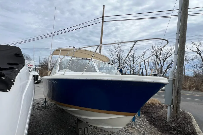 Slide: The Image of 1970 Bertram 25 Moppie boat with blue hull, parked outdoors on gravel. - 11