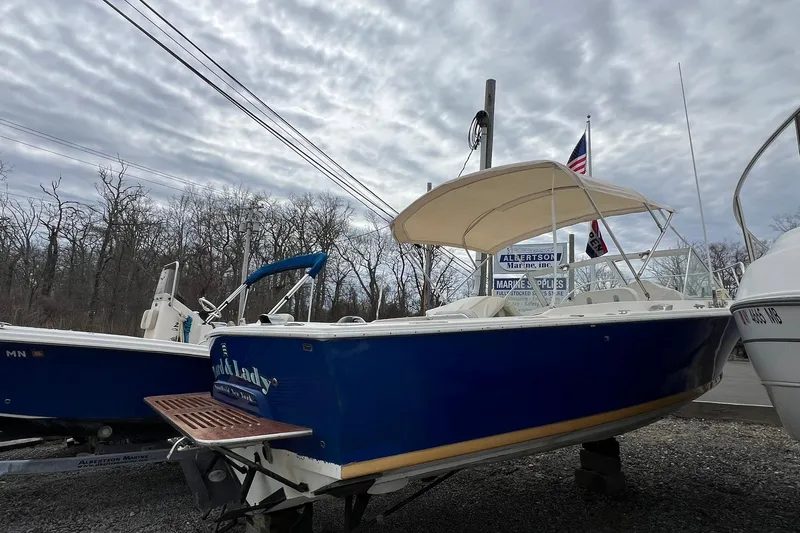 Slide: The Image of 1970 Bertram 25 Moppie boat with canopy, displayed outdoors under cloudy sky. - 12