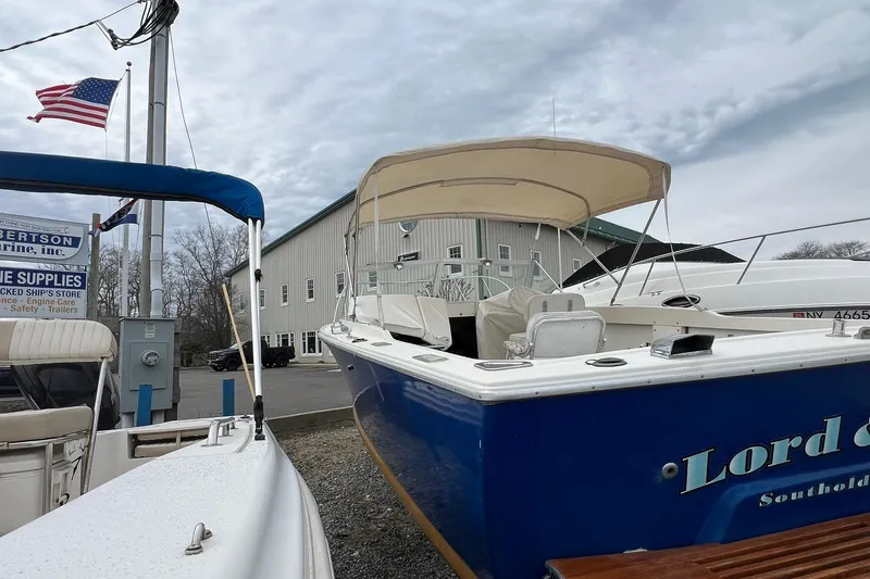 Slide: The Image of 1970 Bertram 25 Moppie boat docked near marine supply store, American flag waving. - 14