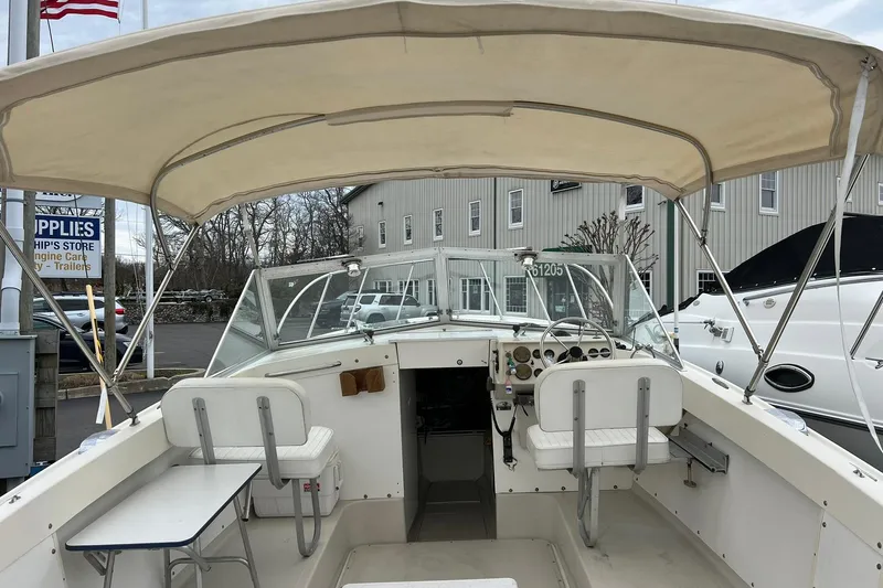 Slide: The Image of 1970 Bertram 25 Moppie boat interior with canopy, docked near a marine supply store. - 35