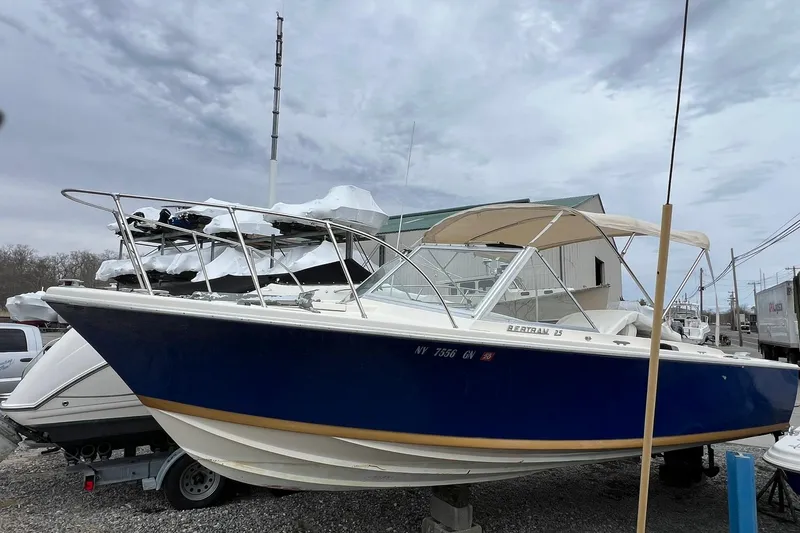 Slide: The Image of 1970 Bertram 25 Moppie boat with blue hull, parked outdoors under cloudy sky. - 9