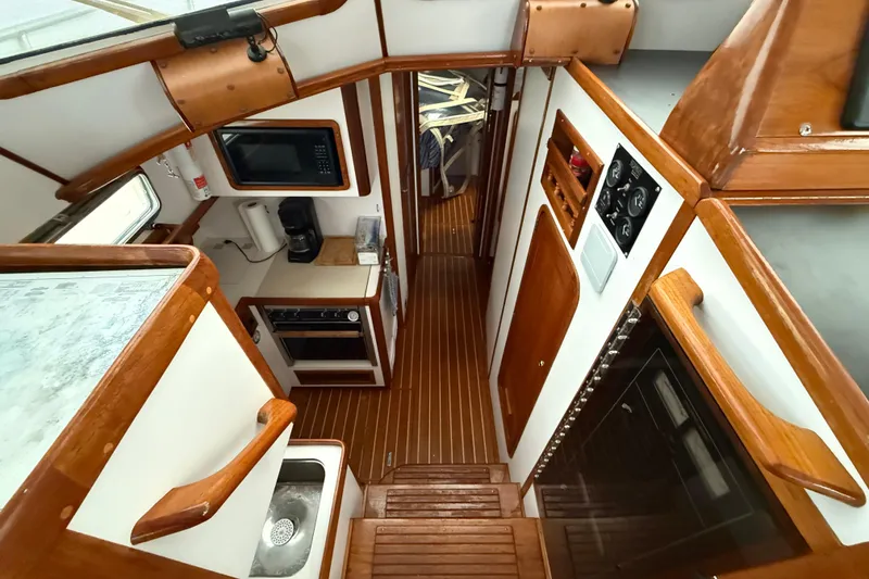 Slide: The Image of Interior of 1996 Legacy Yachts 40, featuring a compact kitchen with wood accents. - 10
