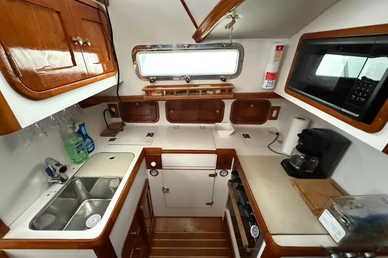 Slide: The Image of Legacy Yachts 40, 1996 model, features a compact, well-equipped galley with wooden cabinetry. - 12