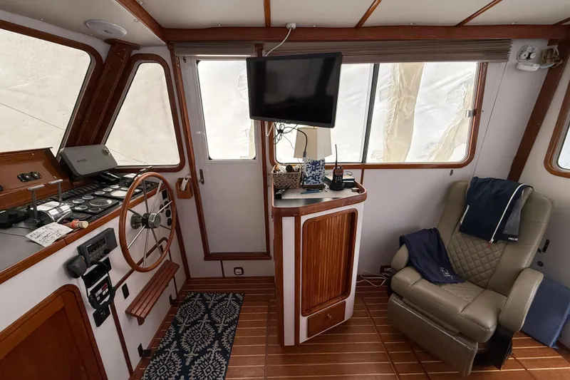 Slide: The Image of Interior of 1996 Legacy Yachts 40, featuring helm, chair, and TV in cozy cabin. - 6