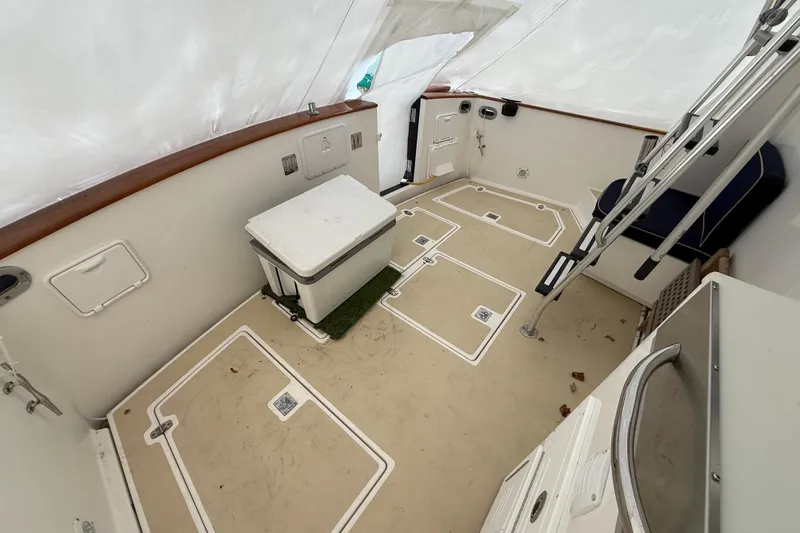 Slide: The Image of 1996 Legacy Yachts 40 cockpit with seating, storage, and ladder under protective cover. - 19