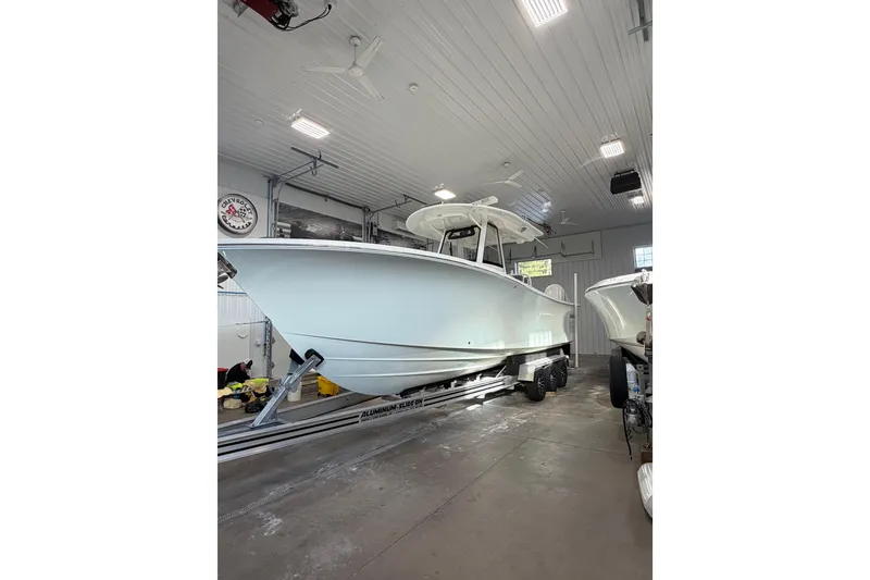 The Image of 2023 Regulator 31 boat in a well-lit garage on a trailer. - 0