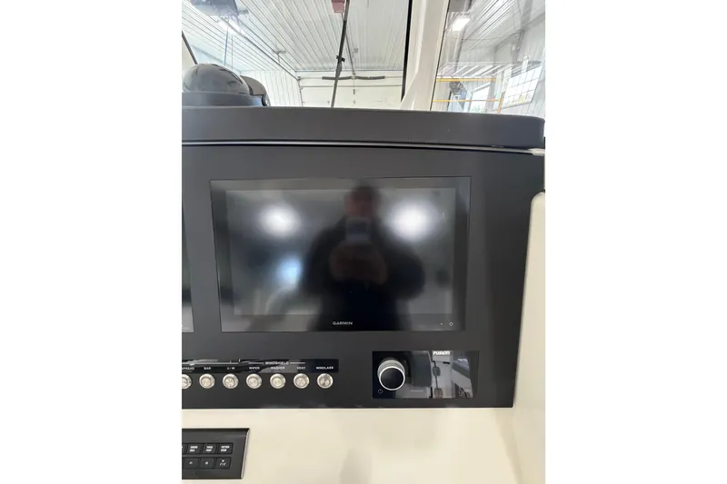 Slide: The Image of 2023 Regulator 31 boat dashboard featuring a Garmin display and control panel. - 14