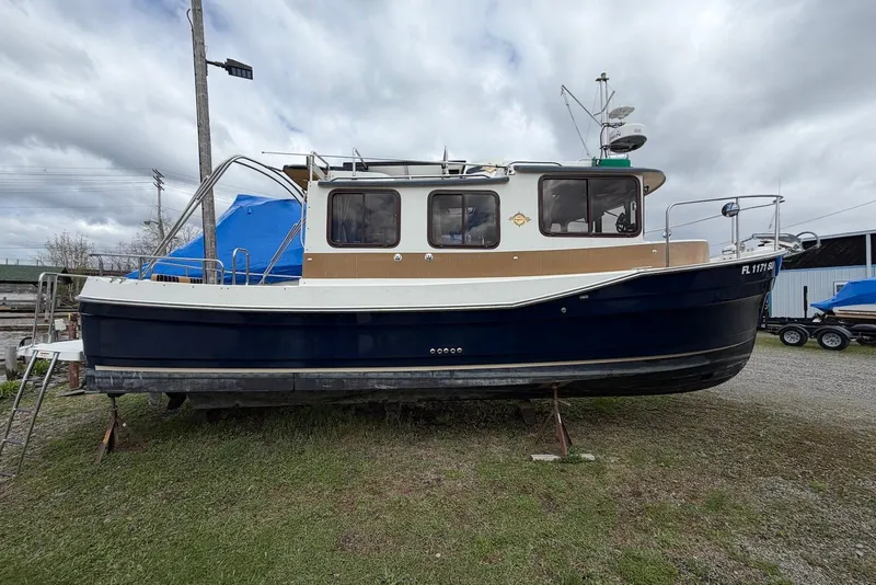 Slide: The Image of 2014 Ranger Tugs R-27 boat on land, blue hull, docked near water. - 11