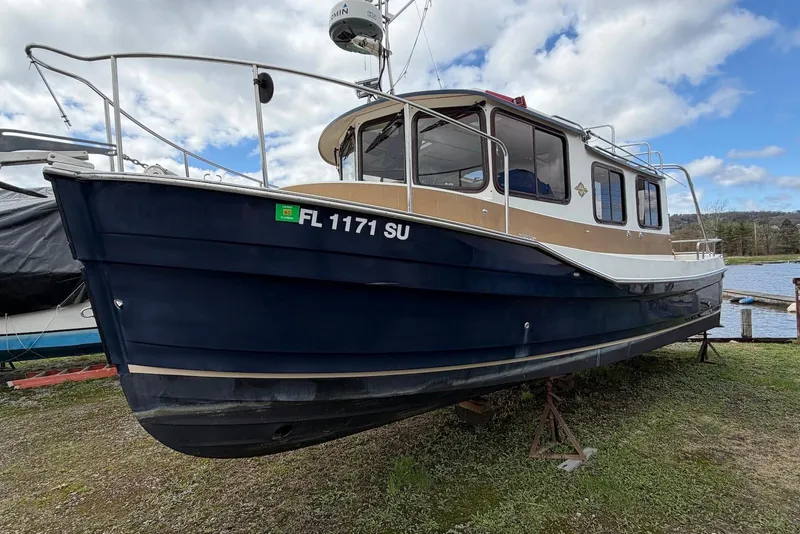Slide: The Image of 2014 Ranger Tugs R-27 boat hull on grassy ground, showcasing bottom details. - 13