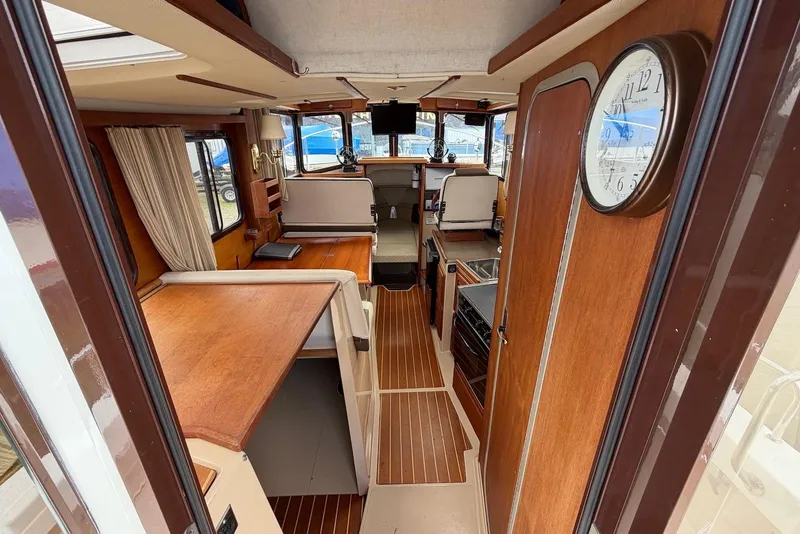 Slide: The Image of 2014 Ranger Tugs R-27 interior with kitchenette, featuring stove, sink, and wood cabinetry. - 18