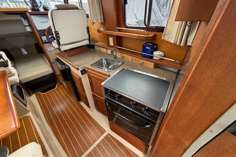 Slide: The Image of 2014 Ranger Tugs R-27 boat bathroom with sink, toilet, and window view. - 19