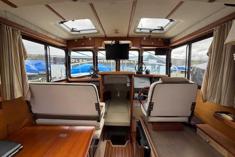 Slide: The Image of 2014 Ranger Tugs R-27 cabin interior with cushioned berth and control panel. - 22