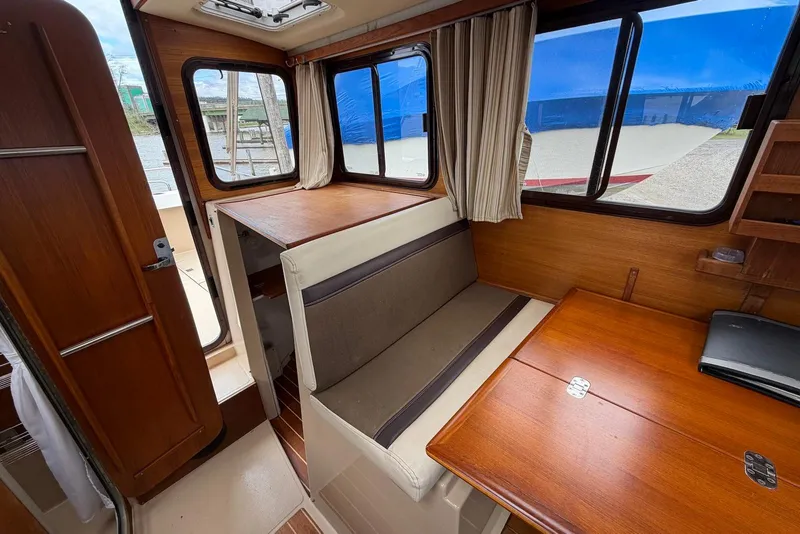 Slide: The Image of 2014 Ranger Tugs R-27 interior with wooden table and cushioned seating. - 24