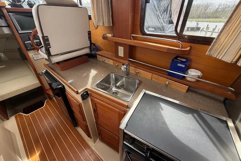 Slide: The Image of 2014 Ranger Tugs R-27 interior with kitchenette, sink, and steering wheel. - 32