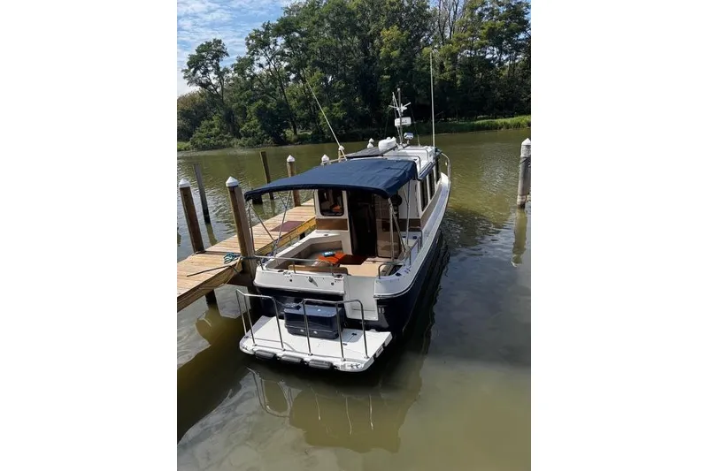 Slide: The Image of 2014 Ranger Tugs R-27 docked on a calm river with lush greenery. - 4