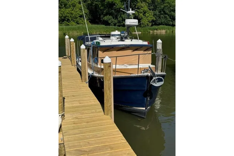 Slide: The Image of 2014 Ranger Tugs R-27 docked on a wooden pier, surrounded by greenery. - 5