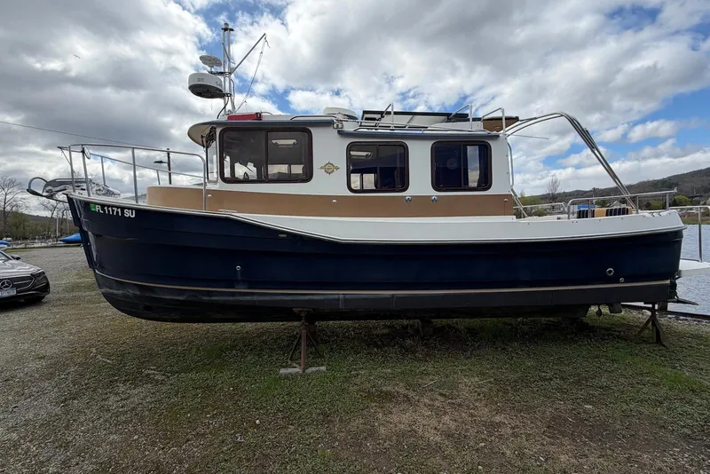 Slide: The Image of 2014 Ranger Tugs R-27 boat docked on grassy area near marina. - 7