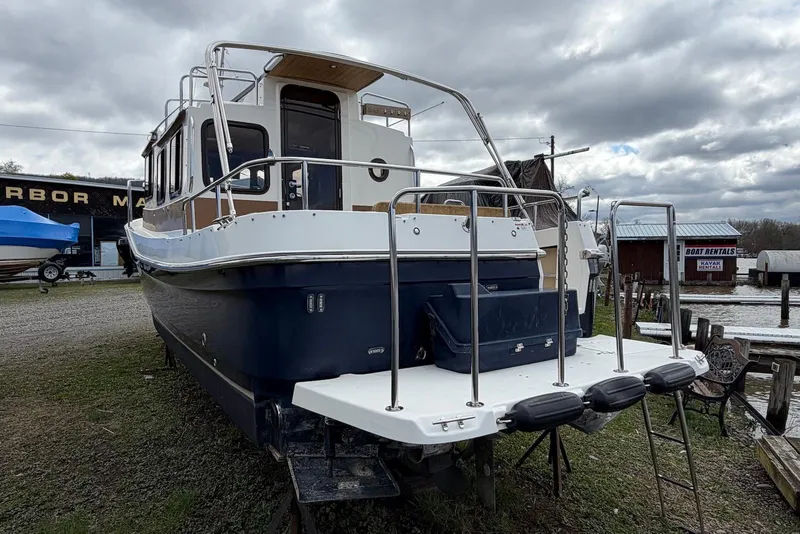 Slide: The Image of 2014 Ranger Tugs R-27 boat on land near a lake with cloudy sky. - 8