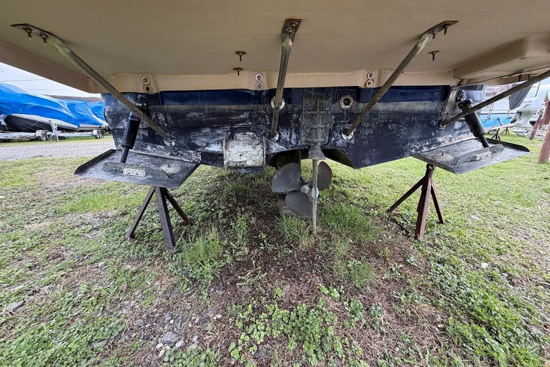 Slide: The Image of 2014 Ranger Tugs R-27 boat hull and propeller on stands, grassy ground. - 9