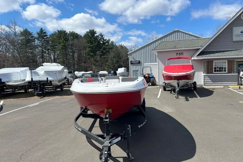 Slide: The Image of 2025 Tahoe T18 boat in dealership lot, surrounded by trees and buildings. - 11