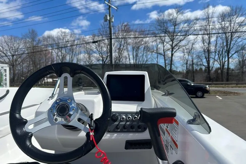Slide: The Image of 2025 Tahoe T18 boat dashboard with steering wheel and control panel under blue sky. - 13