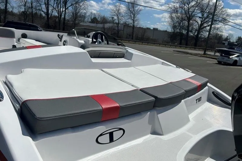 Slide: The Image of 2025 Tahoe T18 boat interior with cushioned seating, parked outdoors under a blue sky. - 16