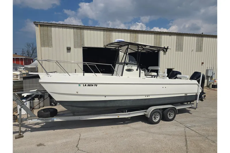 The Image of 2002 Sport-Craft Seacat 255 boat on trailer, parked outside a warehouse. - 0