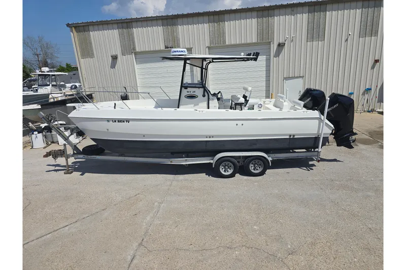 Slide: The Image of 2002 Sport-Craft Seacat 255 boat on trailer, parked outdoors near a warehouse. - 24