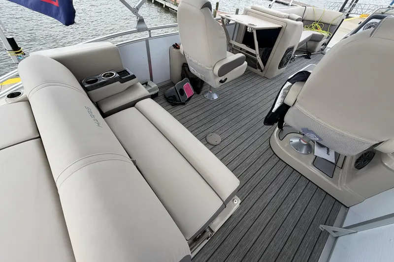 Slide: The Image of 2022 Harris FloteBote Solstice 250 interior with beige seating and cup holders on a boat deck. - 10
