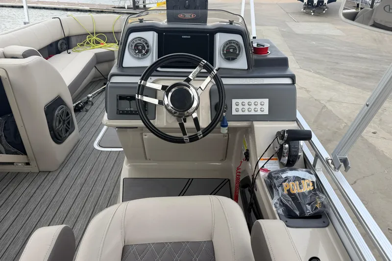 Slide: The Image of 2022 Harris FloteBote Solstice 250 boat dashboard with steering wheel and police cap. - 11
