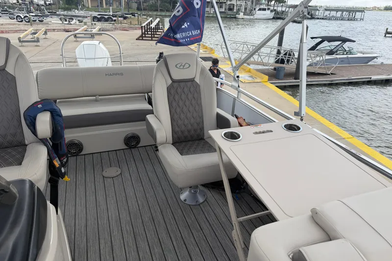 Slide: The Image of 2022 Harris FloteBote Solstice 250 interior with seating and table, docked by the water. - 14