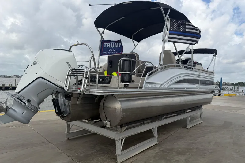 Slide: The Image of 2022 Harris FloteBote Solstice 250 pontoon boat docked with canopy and outboard motor. - 2