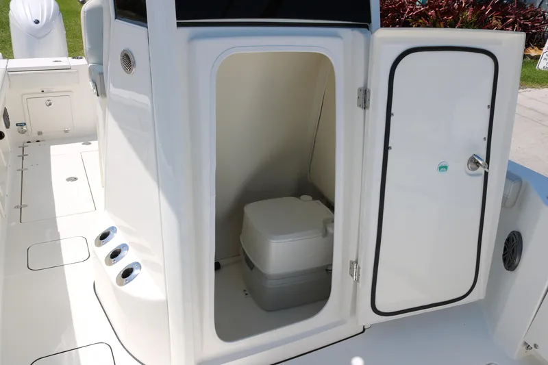 Slide: The Image of 2026 World Cat 235 TE boat interior with open door revealing compact toilet. - 14