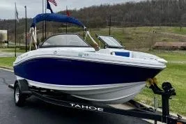 The Image of 2020 Tahoe 450 TF boat on trailer, blue and white design, parked outdoors. - 1