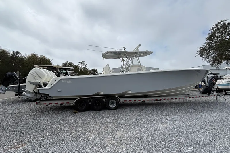 Slide: The Image of 2018 SeaVee 390Z boat on trailer, parked on gravel lot under cloudy sky. - 1