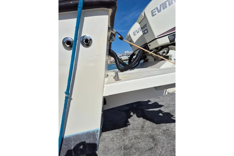 Slide: The Image of 1987 Mako 261 Center Console boat with Evinrude engine, docked under clear blue sky. - 10