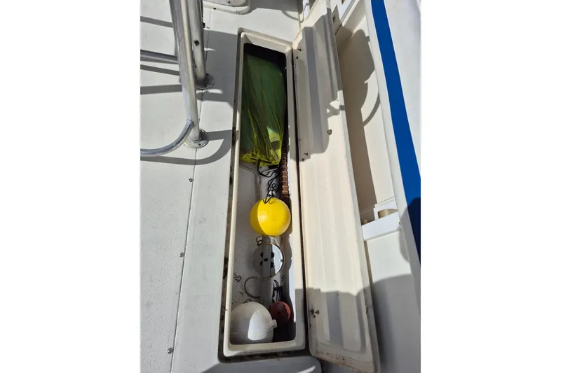 Slide: The Image of 1987 Mako 261 Center Console storage compartment with marine equipment and accessories. - 29