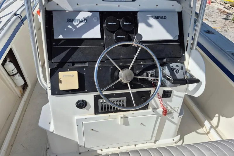 Slide: The Image of 1987 Mako 261 Center Console boat dashboard with steering wheel and Simrad electronics. - 31